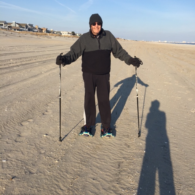 man posing with snowshoes and poles on sand