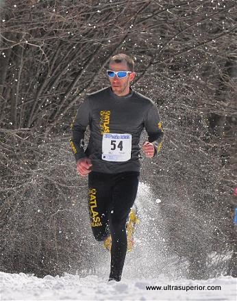 man racing in snowshoes with trees behind him