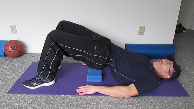 person demonstrating of bridge pose with yoga block