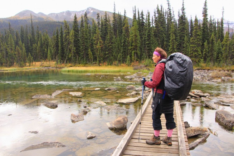 woman standing on bridge while backpacking