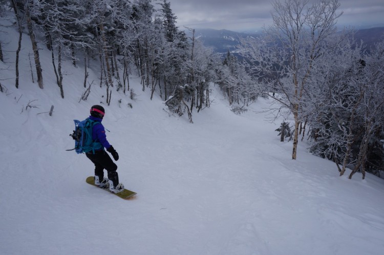 back view of man backcountry snowboarding