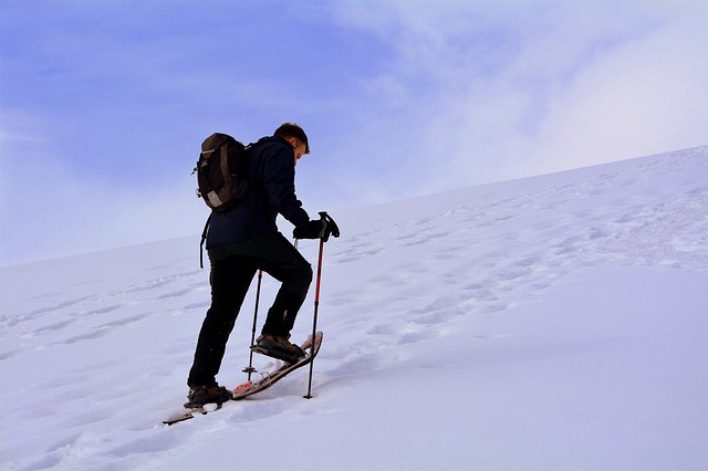 man ascending a hill in snowshoes