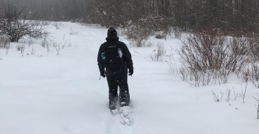 man snowshoeing in deep snow with Dion 164 snowshoes