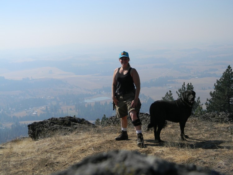 snowshoeing after ACL replacement: woman with knee brace and dog on top of hill in summer with valley in background