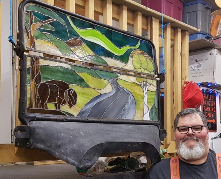 snowshoe artist Canada: man posing next to his stained glass art