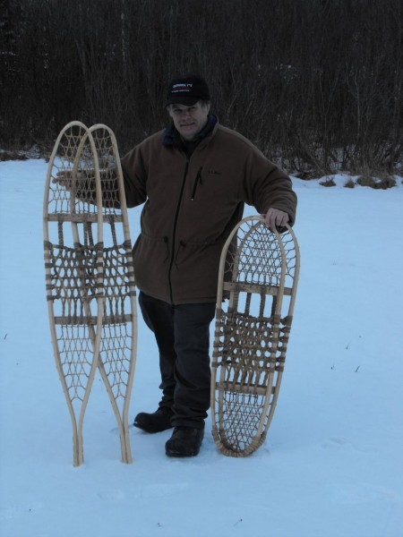 traditional snowshoes: man holding two pairs of traditional snowshoes