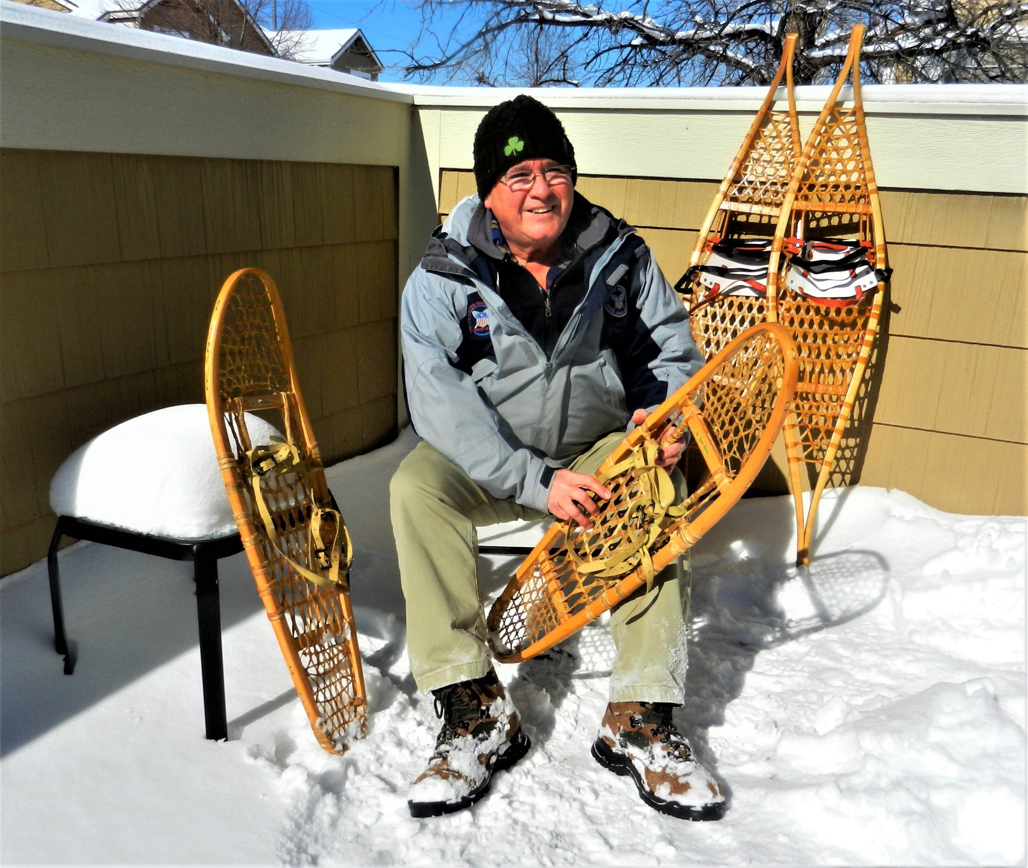 man with traditional snowshoes sitting on chair in snow