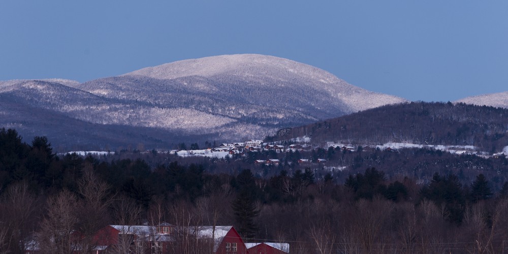 view of a lodge in distance with snowy hill in background