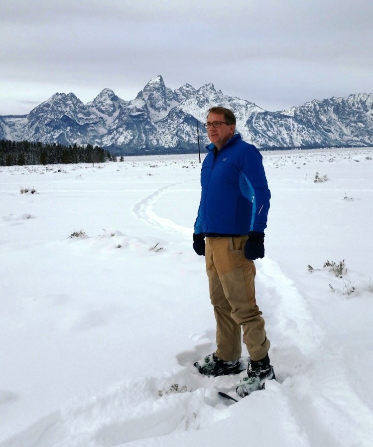man in deep snow with mountains in the background