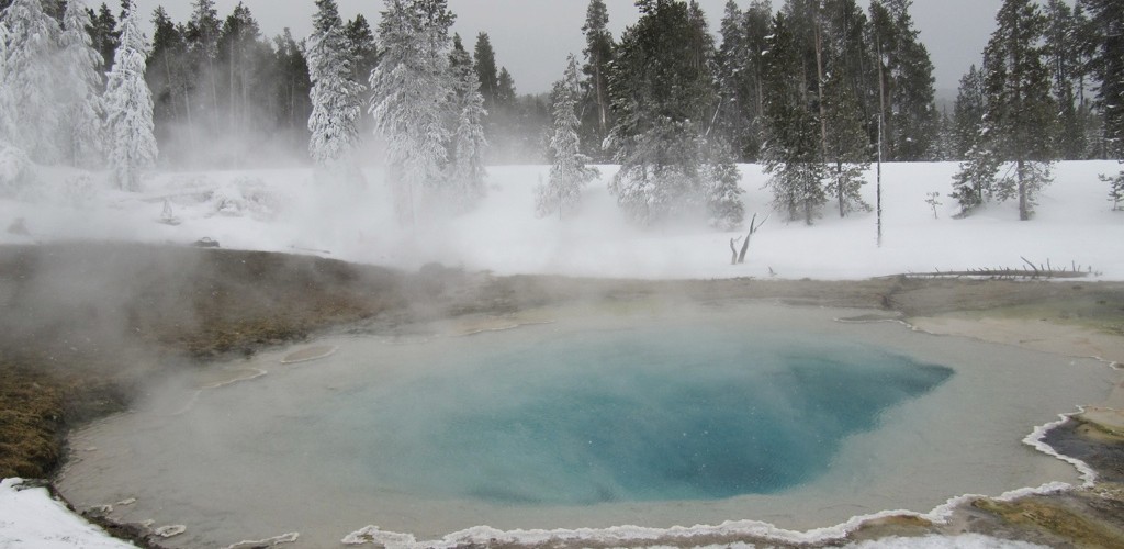geyser in Yellowstone National Park surrounded by snow