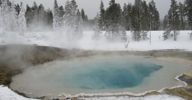 geyser in Yellowstone National Park surrounded by snow