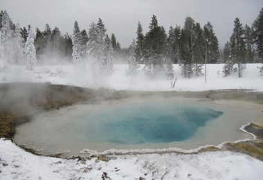 geyser in Yellowstone National Park surrounded by snow