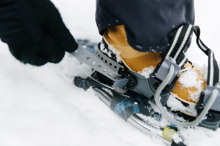 person pulling heel strap on snowshoe