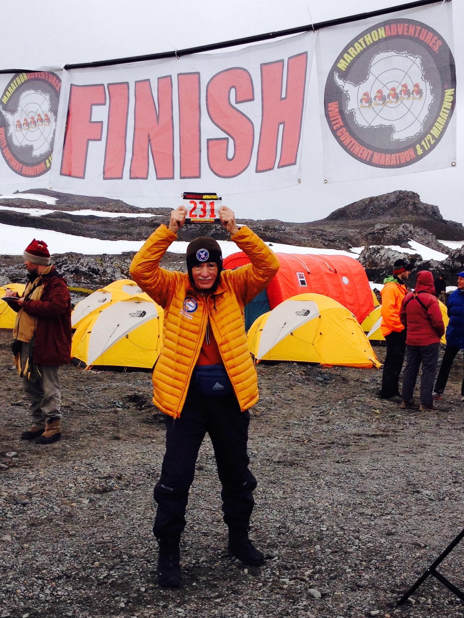 man holding up his racing number after his tenth completion of the continents
