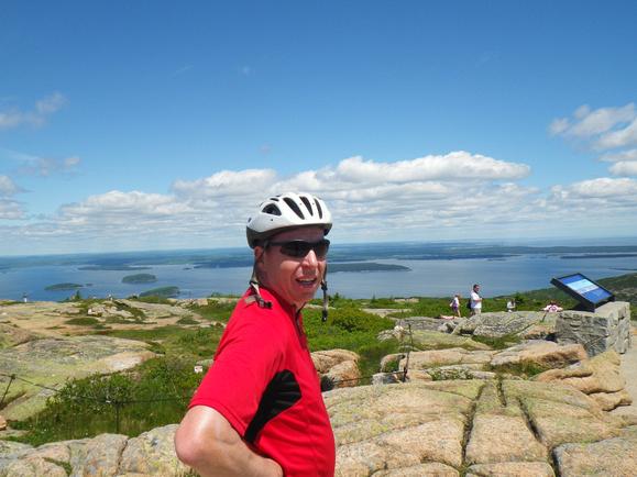 man with bike helmet posing in front of trails and ocean view