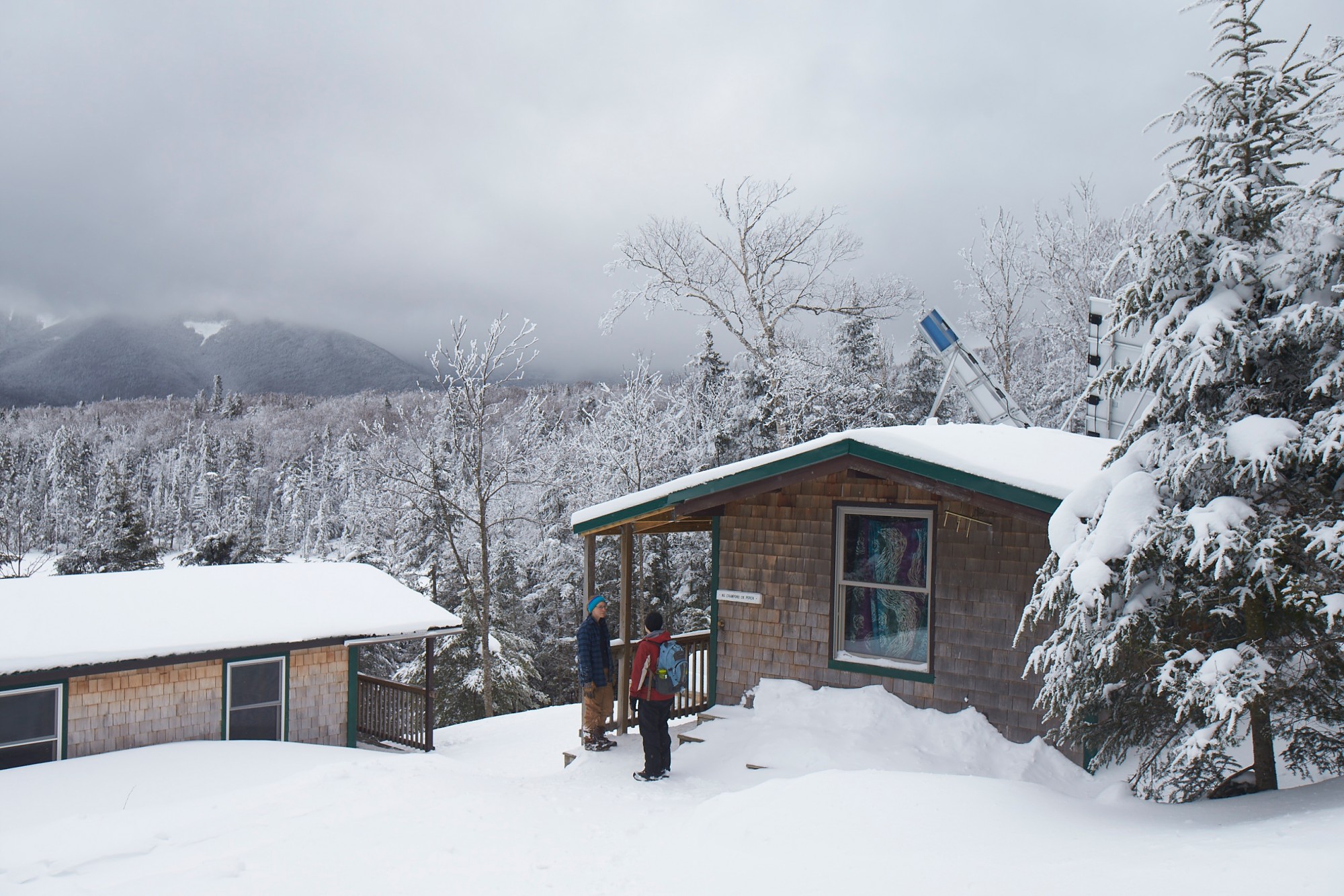 snowshoe bucket list: snow covered hut with trees in background in White Mountains