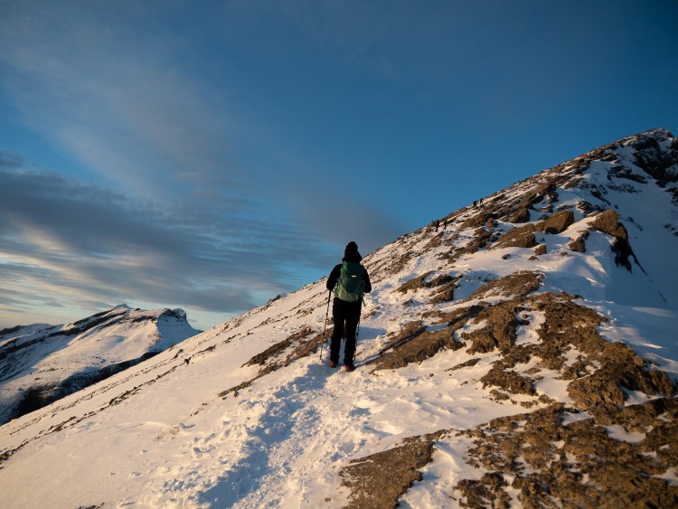 person walking on snowshoe trail on mountain