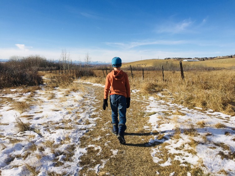 boy walking on trail partly covered by snow