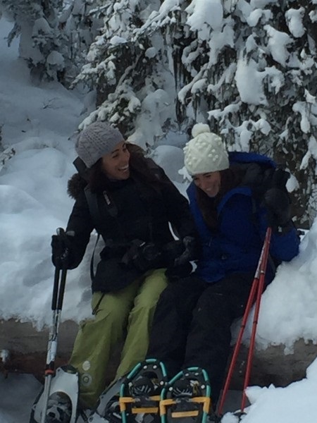 two females laughing while snowshoeing