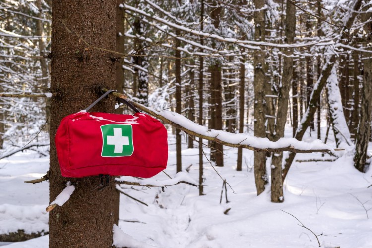 winter hiking safety: first aid kit hanging on tree with snow