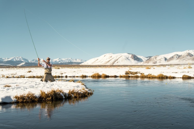 man fishing in winter with snow on ground