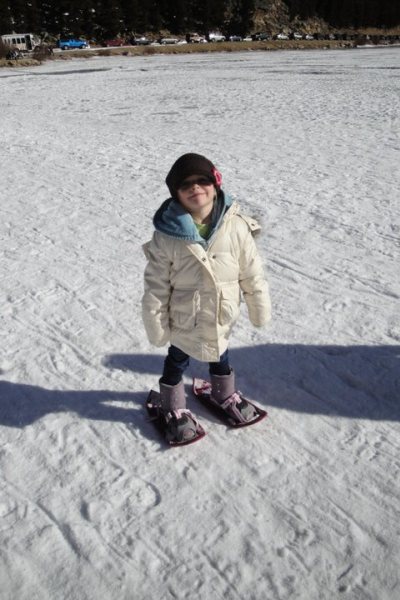 child in snowshoes smiling in the snow