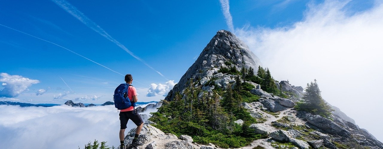 man on mountain top with blue sky above