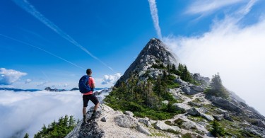 man on mountain top with blue sky above