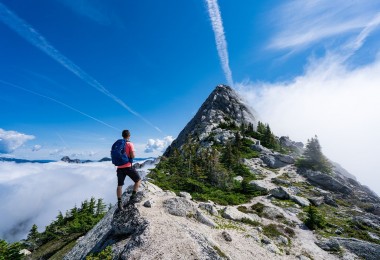 man on mountain top with blue sky above