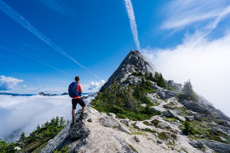 man on mountain top with blue sky above