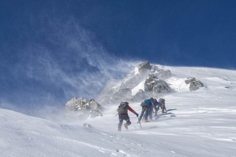snowshoeing safety elevation: people climbing up mountain in winter