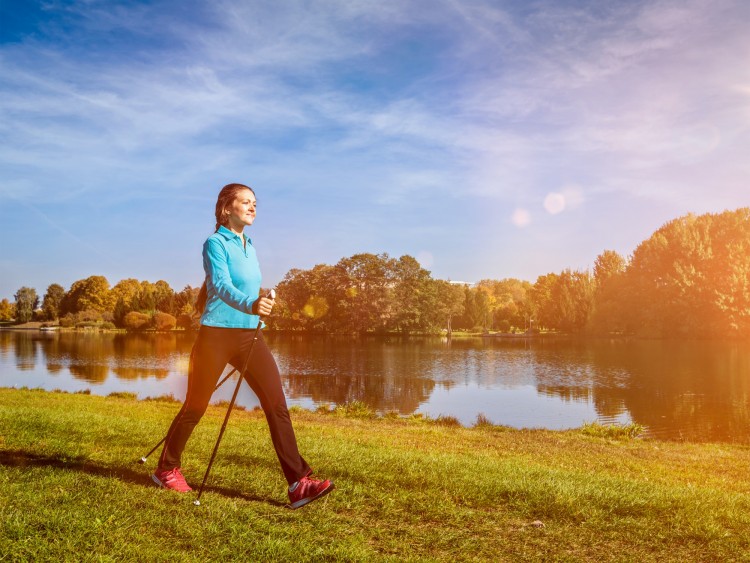 training for snowshoeing: woman walking in park with nordic walking poles