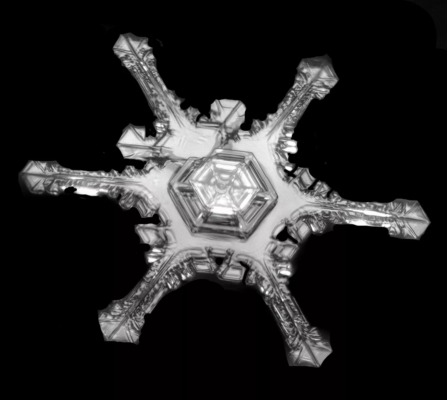 close up image of snowflake with arms of different size on black background