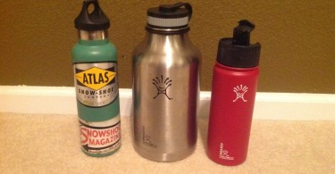 three Hydro Flask bottles sitting next to each other against a wall