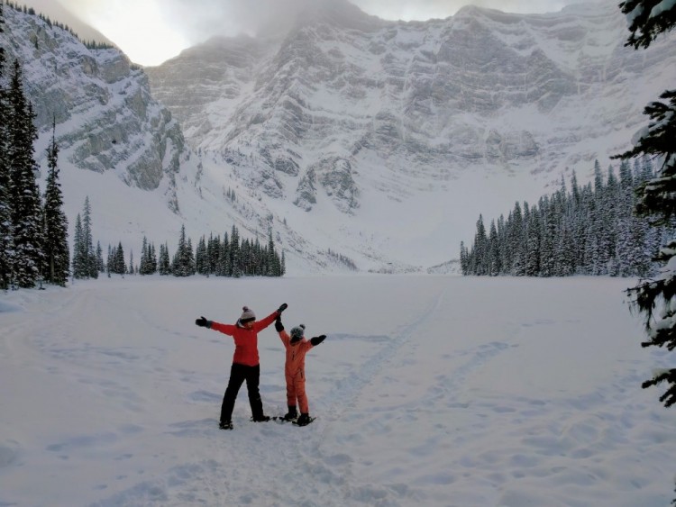 mother and son on snowshoes with arms outstretched at Rawson Lake, Kananaskis