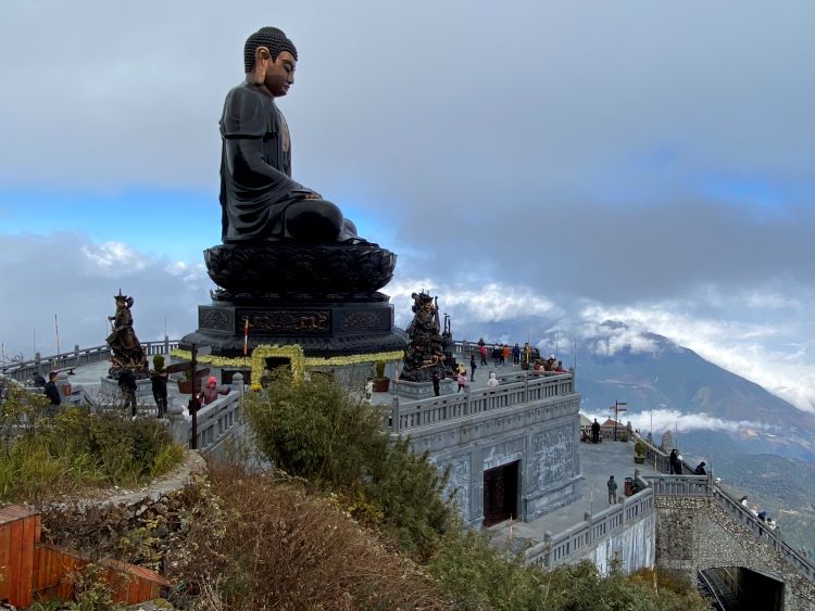 large Buddha sits on mountaintop with clouds in background