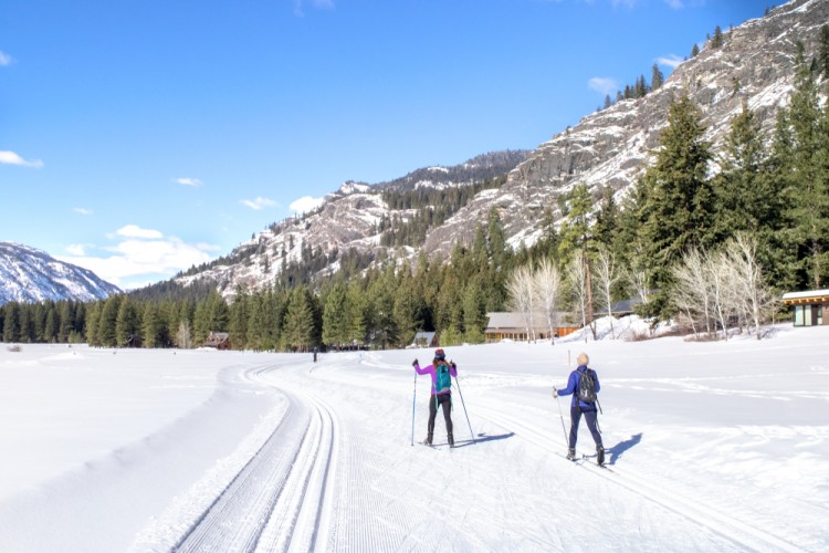 snowshoeing and cross-country skiing for couples: people skiing on snow with mountains in background.