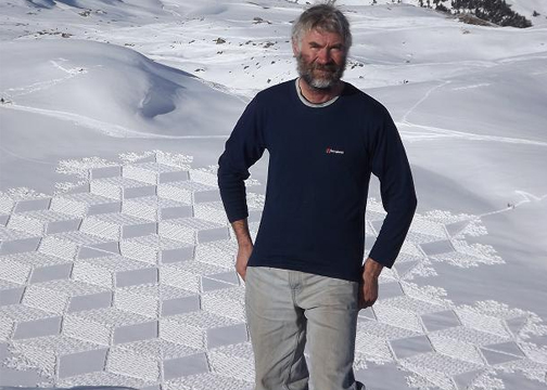 snow artist Simon Beck standing in front of one of his designs