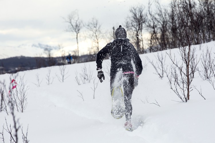 person running on snowshoes near bushes