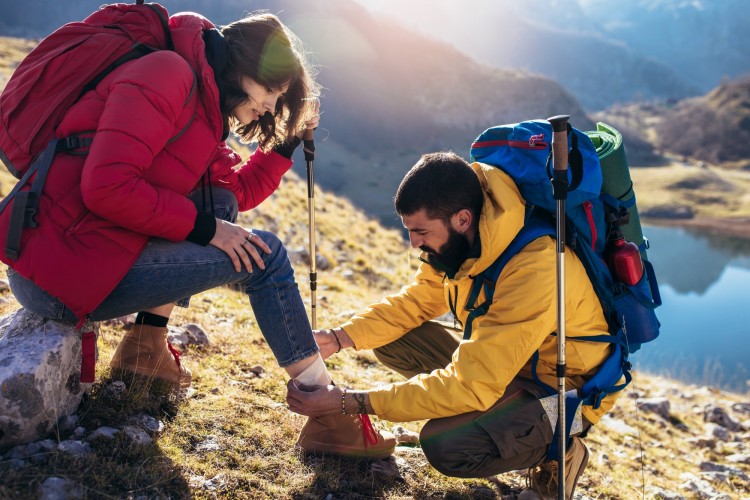 man helps woman to heal sprained ankle while hiking