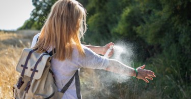 woman spraying mosquito repellant in outdoors