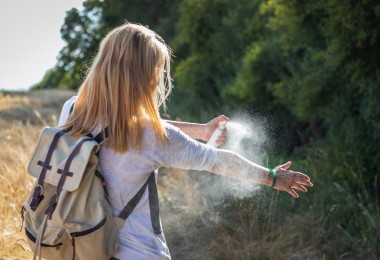 woman spraying mosquito repellant in outdoors