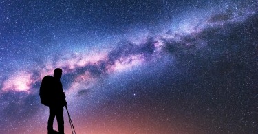 man silhouette in front of starry multi-colored sky