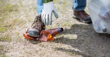 woman reaching down to clean up trash